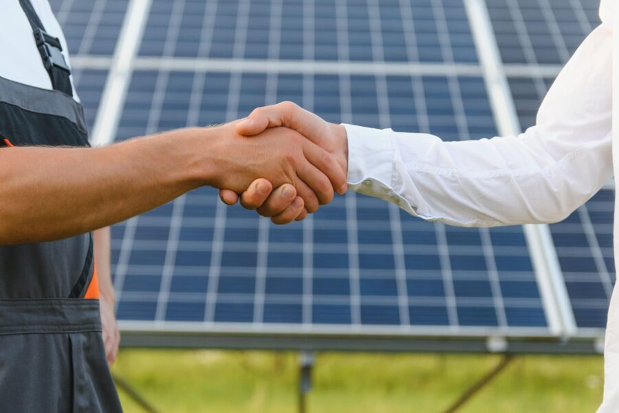 persone che si stringono la mano con dietro un pannello solare